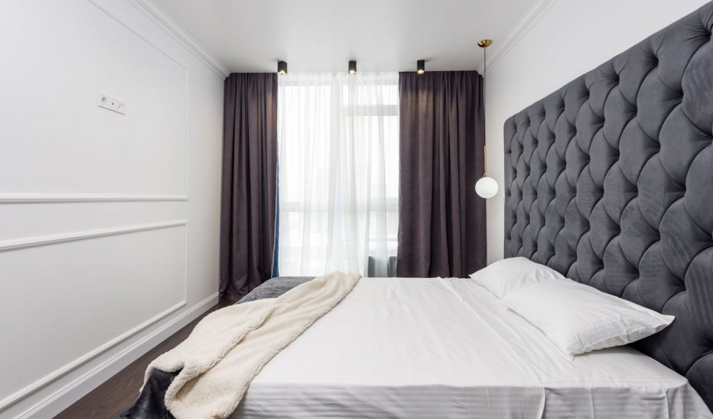 sypialnia z dużym łóżkiem i panelami tapicerowanymi na ścianie