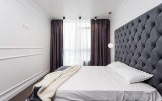 sypialnia z dużym łóżkiem i panelami tapicerowanymi na ścianie