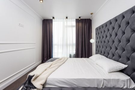 sypialnia z dużym łóżkiem i panelami tapicerowanymi na ścianie